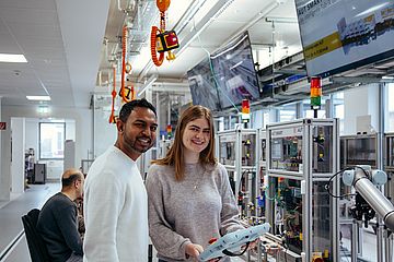 Zwei Studierende programmieren in der Digitalen Modellfabrik einen Roboter