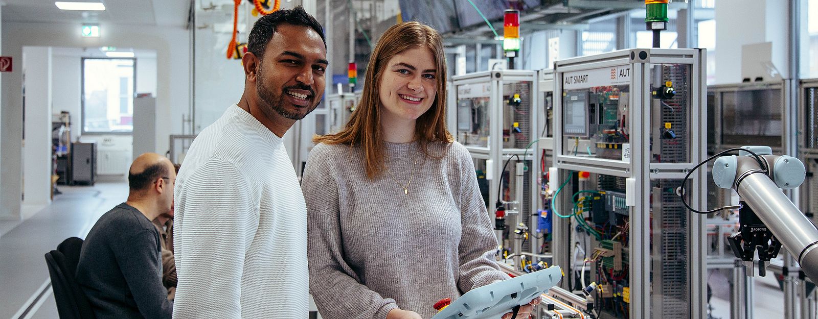 Zwei Studierende programmieren in der Digitalen Modellfabrik einen Roboter