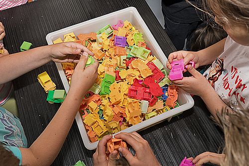 Schülerinnen und Schüler bauen kleine, bunte Spielzeugautos zusammen